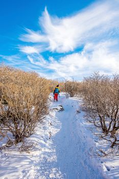 Woman walking on trail with snow in mountains.