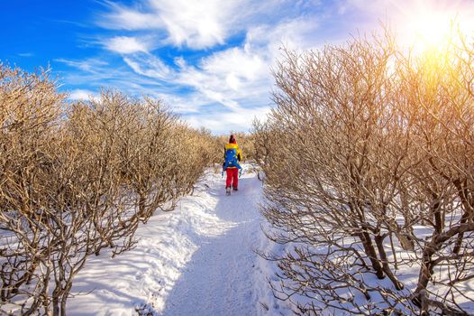 Woman walking on trail with snow in mountains.