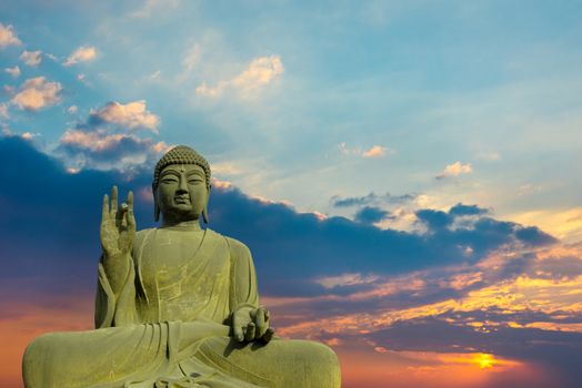 Statue of Buddha at peace with sunset background.