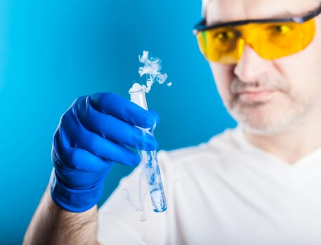 man chemist examines test tube on a blue background