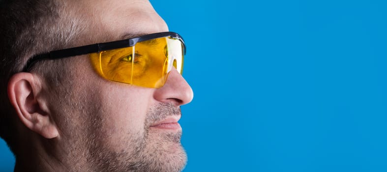 man in glasses working on a blue background