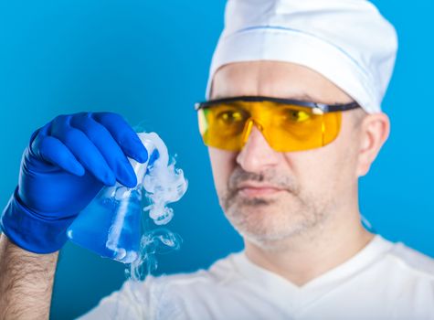 man chemist examines test tube on a blue background