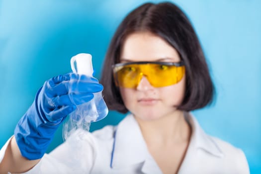 Woman chemist examines test tube on a blue background