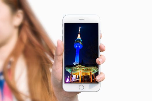 Hand holding smart phone with photo of Seoul tower isolated on white background.