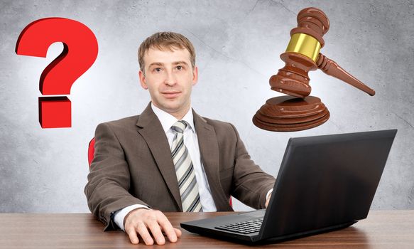 Businessman working on laptop with question sign and gavel, justice concept