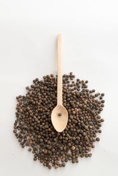 Black pepper and wooden spoon on white background