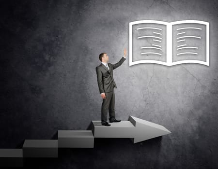 Businessman touching book sign standing on stairs, business concept