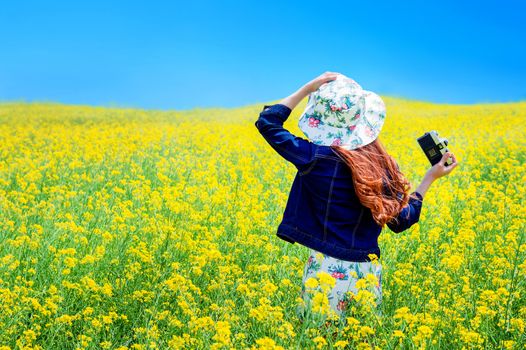Young woman standing in yellow rapeseed field.