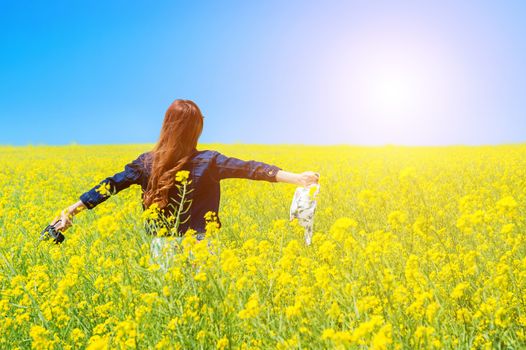 Young woman standing in yellow rapeseed field.
