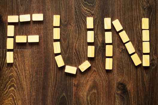 Word fun arranged by wooden blocks on wooden, brown floor.