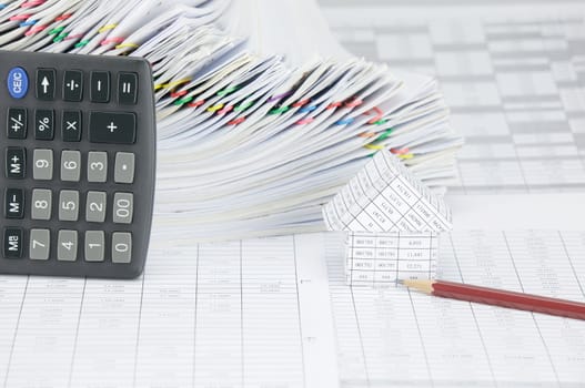 House with brown pencil on finance account have calculator place vertical and overload of paperwork with colorful paperclip as background.