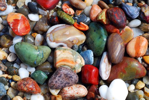 Multicolored sea pebbles in the water on the shore for background or wallpaper.