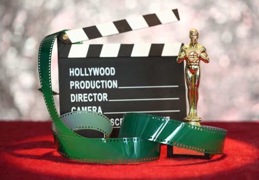 Movie clapper board and film roll in front glittering  background