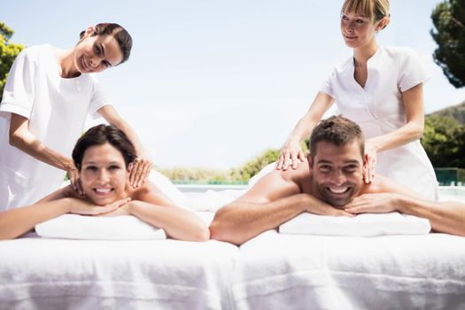 Portrait of relaxed young couple receiving a back massage from masseur in a spa