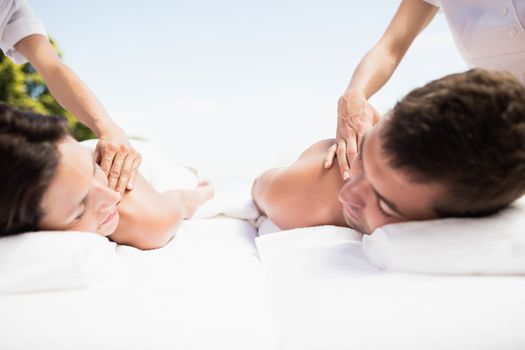 Relaxed young couple receiving a back massage from masseur in a spa