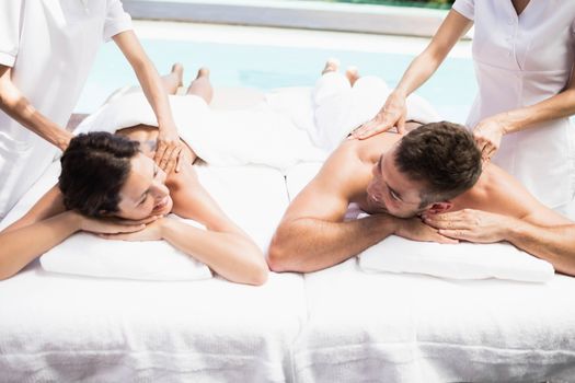 Relaxed young couple receiving a back massage from masseur in a spa