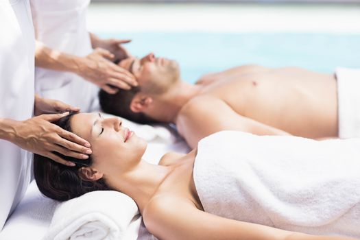 Couple receiving a head massage from masseur in a spa