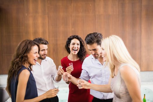 Young and handsome group of friends drinking shots at the party