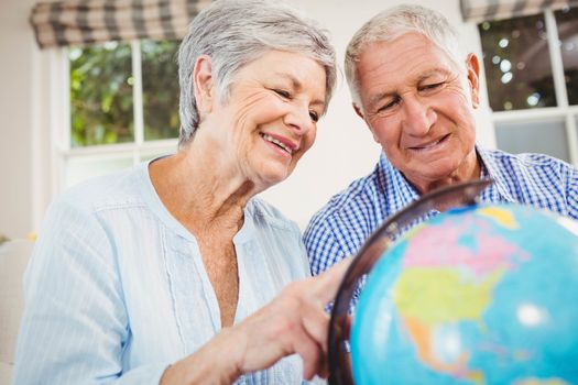 Senior couple sitting on sofa and looking at a globe in living room