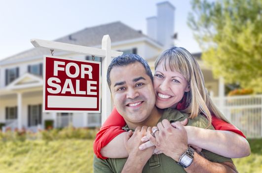 Happy Mixed Race Couple in Front of For Sale Real Estate Sign and New House.