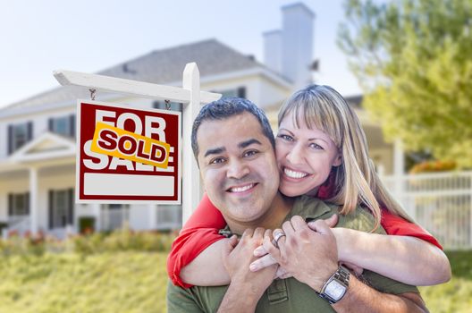 Happy Mixed Race Couple in Front of Sold Home For Sale Real Estate Sign and House.