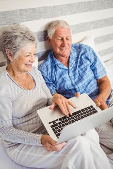 Senior couple using laptop in bedroom