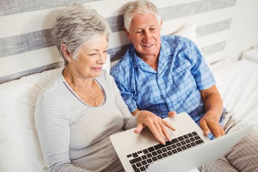 Senior couple using laptop in bedroom