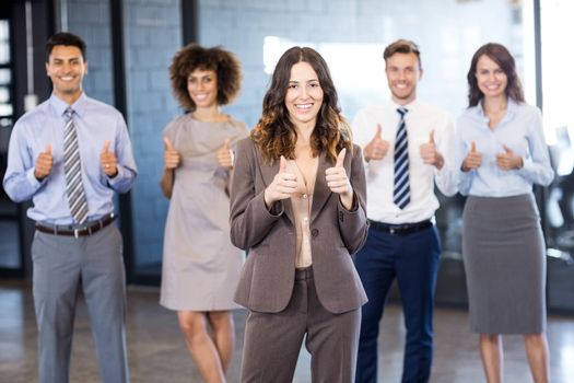 Successful business team holding their thumbs up while celebrating victory in office