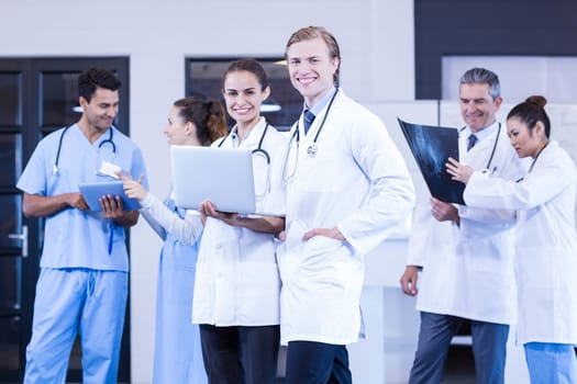 Medical team discussing x-ray report and using laptop and digital tablet in hospital