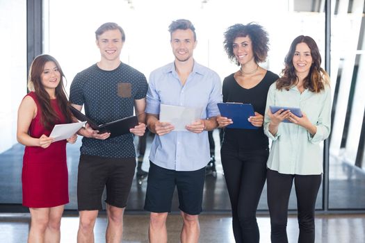 Portrait of colleagues standing in office with document and digital tablet