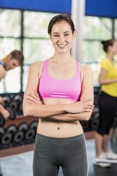 Fit woman posing with athletic women and man behind at crossfit gym