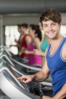 Smiling muscular man on treadmill at gym 