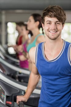 Smiling muscular man on treadmill at gym 