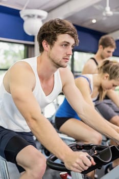 Fit group of people using exercise bike together in crossfit