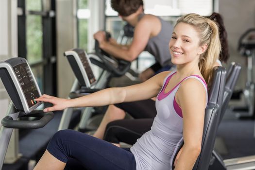 Fit people doing exercise bike at gym