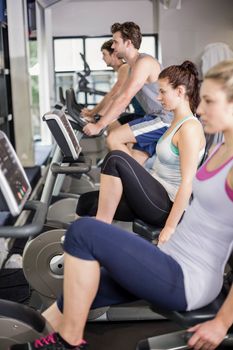 Fit people doing exercise bike at gym