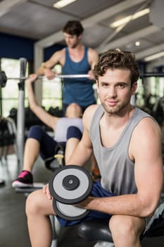 Fit man lifting dumbbell at gym