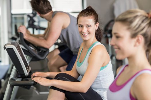 Fit people doing exercise bike at gym