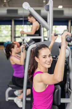 Fit woman using weight machine in gym