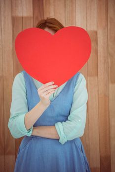 Pretty hipster holding heart on wooden background