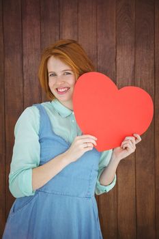 Pretty hipster holding heart on wooden background