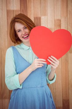 Pretty hipster holding heart on wooden background