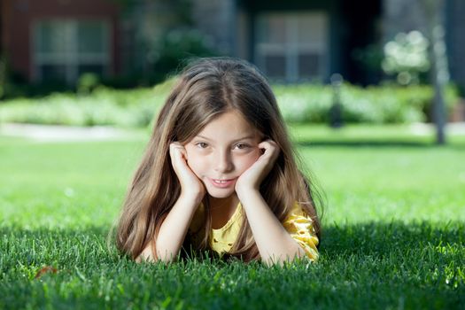 portrait of little girl laying on the grass in summer environment