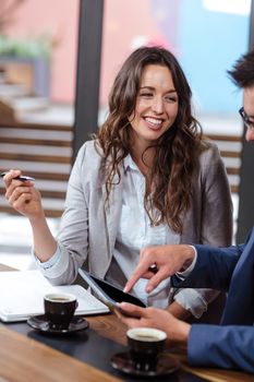 Smiling people talking and using tablet in a cafe