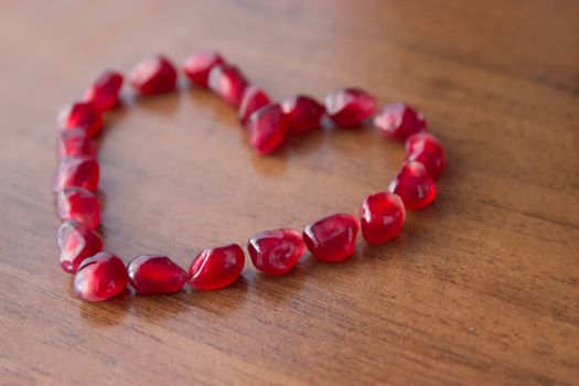 garnet heart shape on wooden table, close up