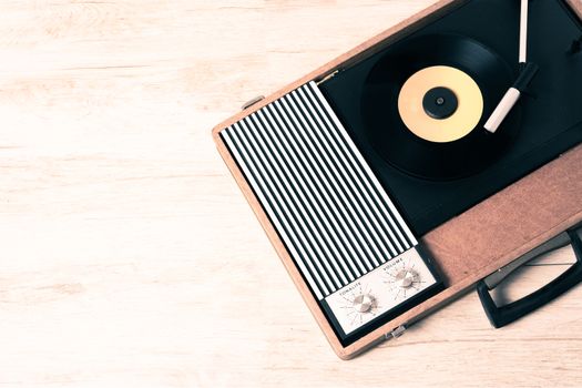 Gramophone with a vinyl record on wooden table, top view and copy space,photo desaturate and split toning for old style.