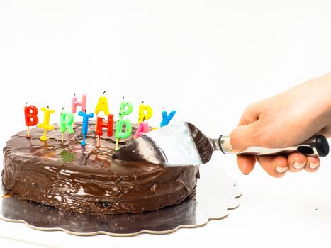 Female person cutting a homemade sacher chocolate cake with birthday candles