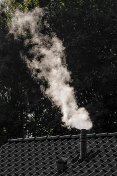 Smoke coming out of a chimney on the roof of a house