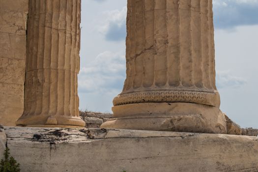 Base of the antique columns at Acropolis in Athens, Greece. Cloudy sky in the background.