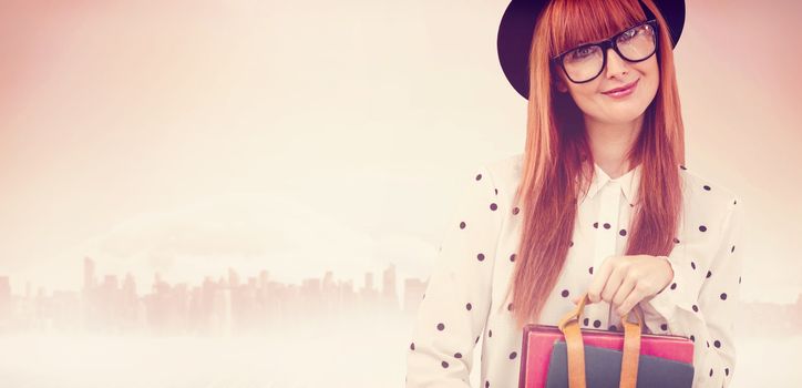 Smiling hipster woman holding book belt  against large city on the horizon